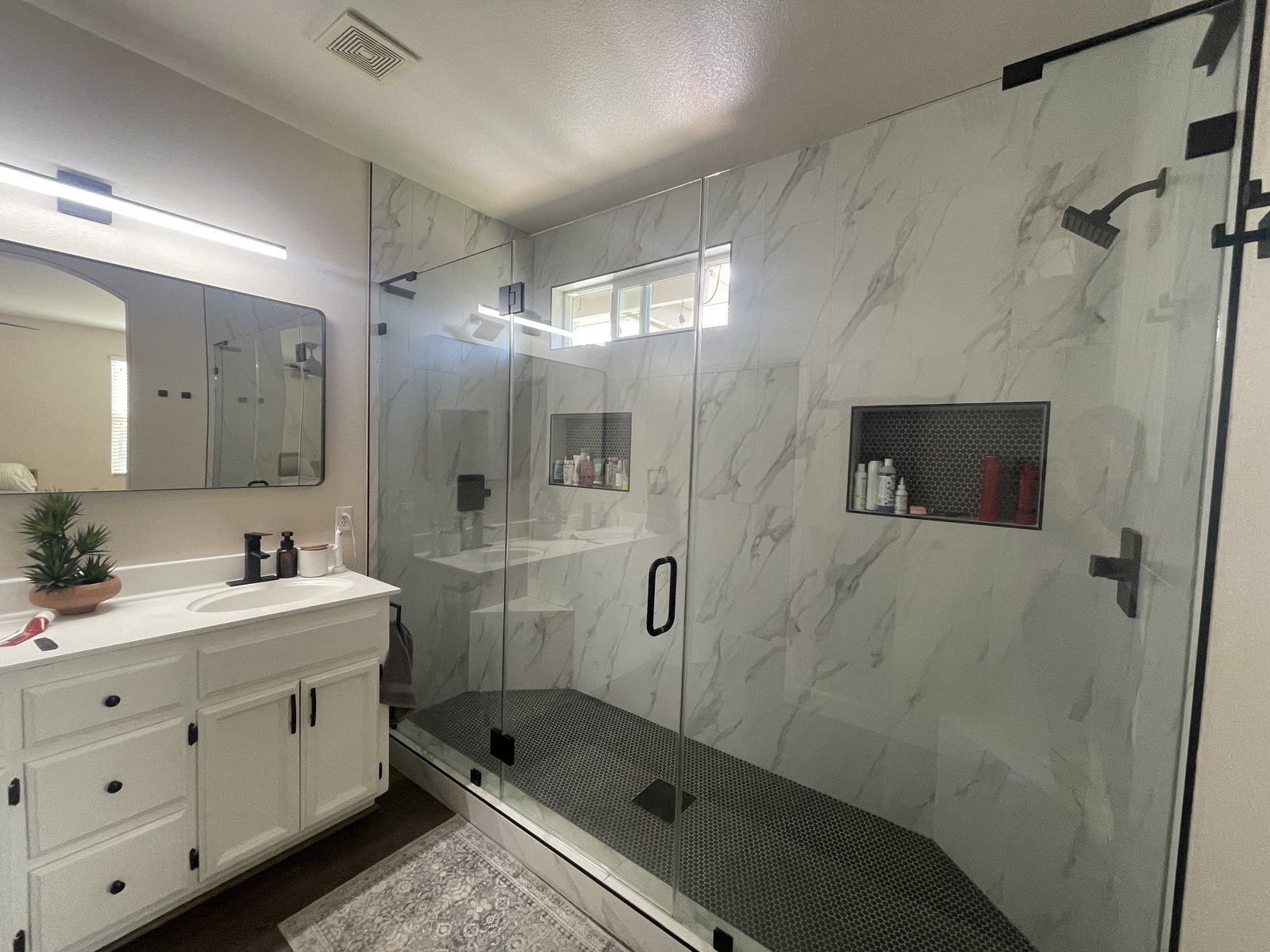A marble-look walk-in shower and white vanity