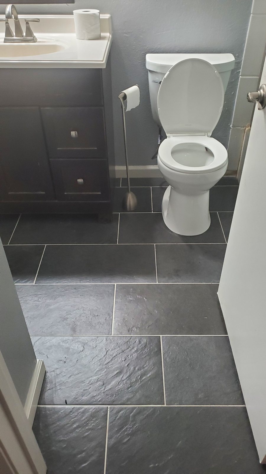 A bathroom with a dark vanity and tiled floor