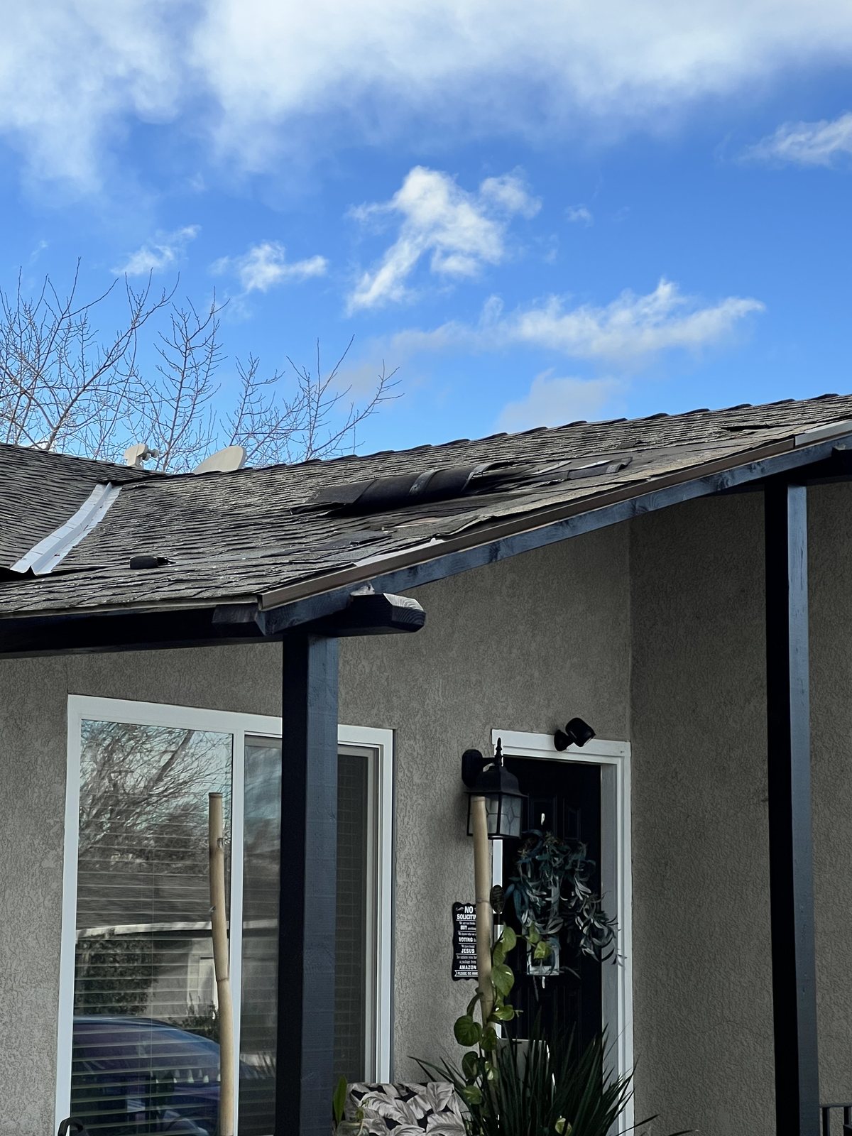 Damaged roof shingles above a home entry